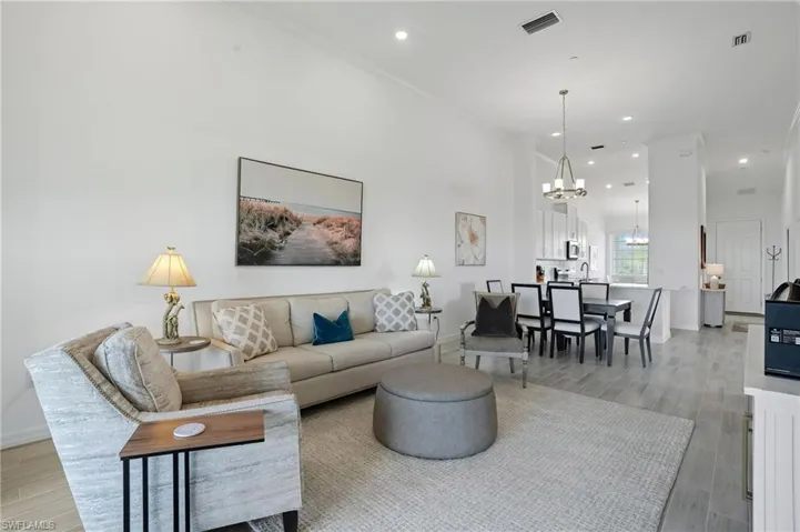 Living area with light wood-type flooring, a chandelier, recessed lighting, and crown molding
