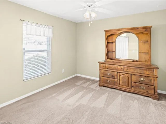 Unfurnished bedroom with light colored carpet and ceiling fan