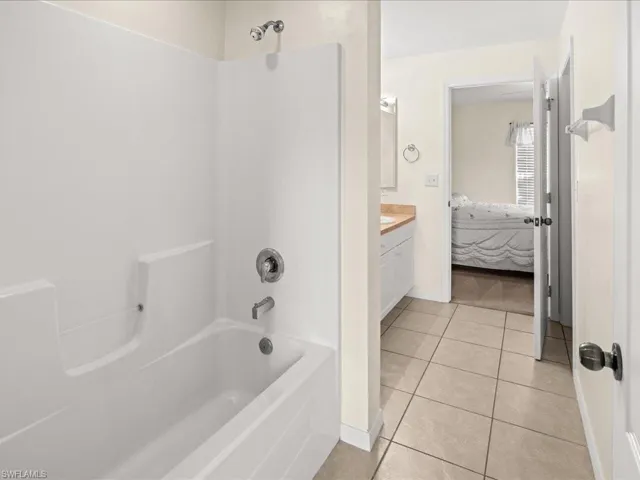 Jack and Jill Ensuite bathroom with vanity, light tile patterned flooring, and shower / bath combination
