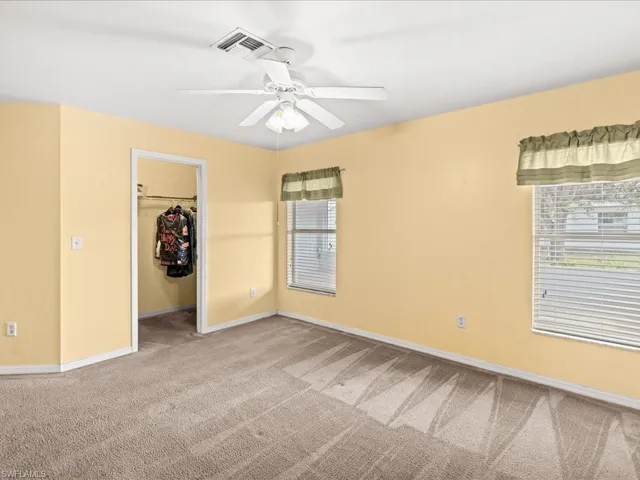 Master Unfurnished bedroom featuring a spacious closet, light colored carpet, and ceiling fan