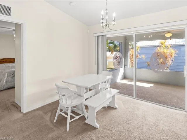 Dining space featuring light colored carpet and a chandelier