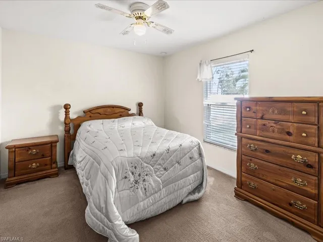 Carpeted bedroom with a ceiling fan and baseboards