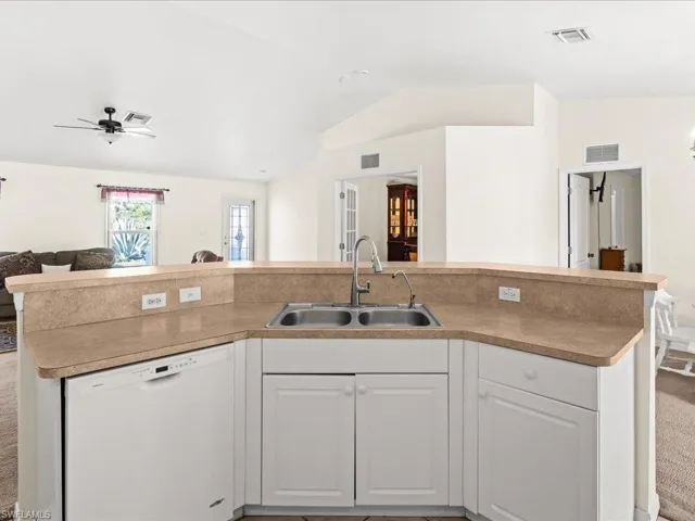 Kitchen with white cabinetry, open floor plan, white dishwasher, lofted ceiling, and a center island with sink