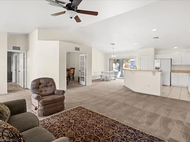 Living room featuring light colored carpet, vaulted ceiling, a ceiling fan, and french doors