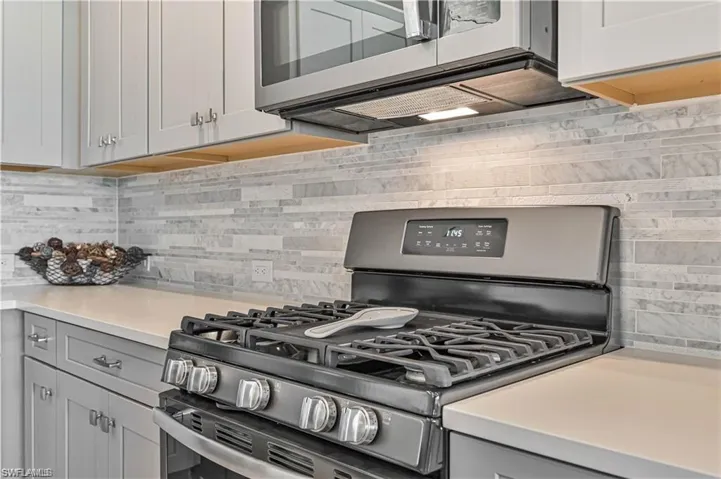 Kitchen featuring appliances with stainless steel finishes, gray cabinets, and backsplash