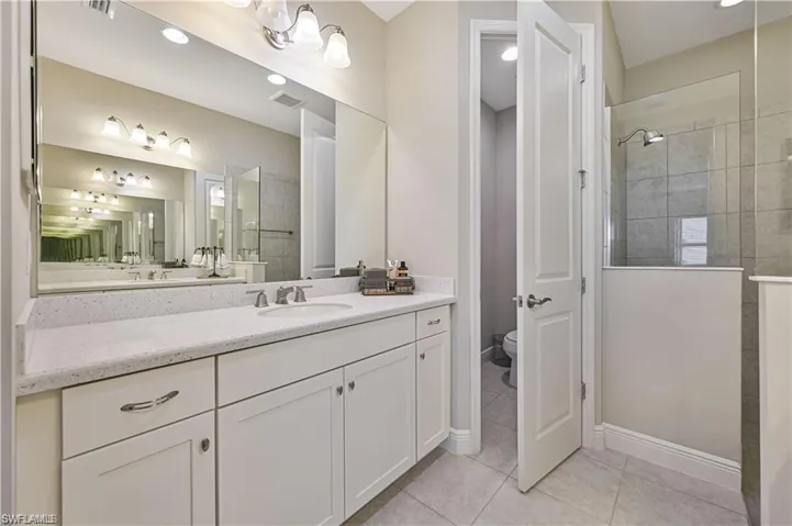 Bathroom featuring a tile shower, vanity, toilet, and tile patterned floors