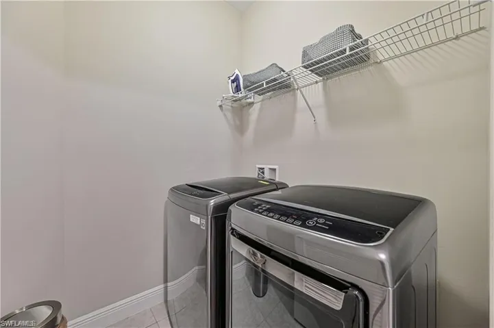 Clothes washing area featuring washer and clothes dryer and light tile patterned flooring