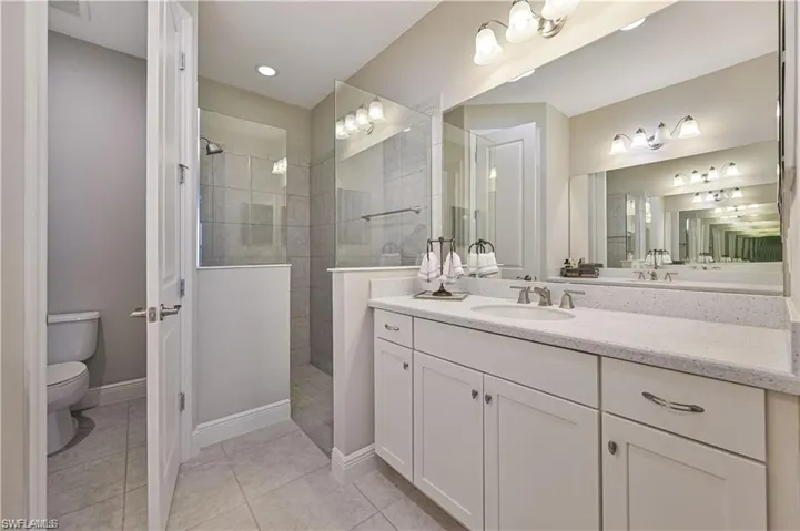 Bathroom with a tile shower, vanity, toilet, and tile patterned floors