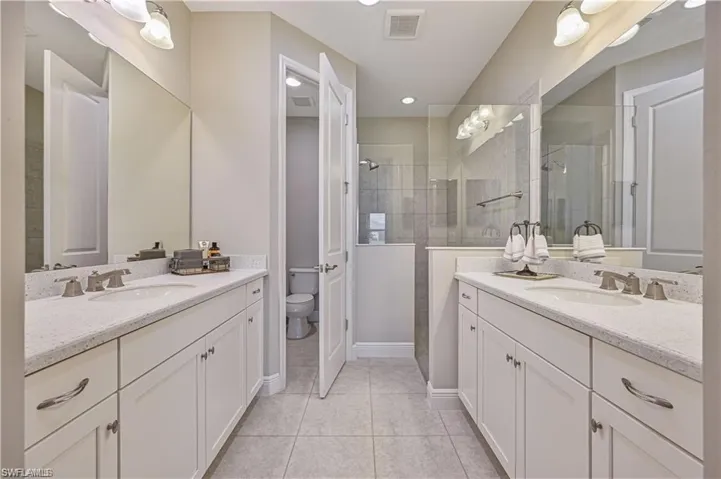 Bathroom featuring a tile shower, vanity, toilet, and tile patterned floors