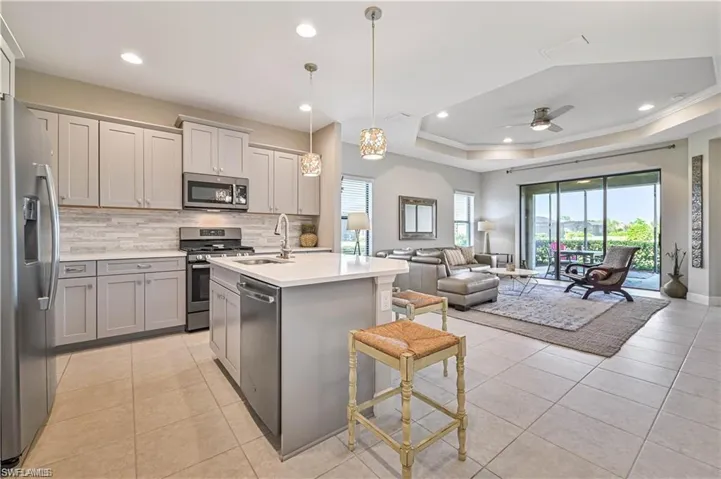Kitchen featuring a kitchen island with sink, stainless steel appliances, a breakfast bar area, hanging light fixtures, and backsplash