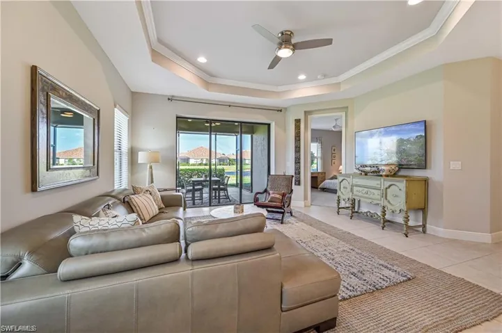 Living room featuring ceiling fan, ornamental molding, a raised ceiling, and light tile patterned floors