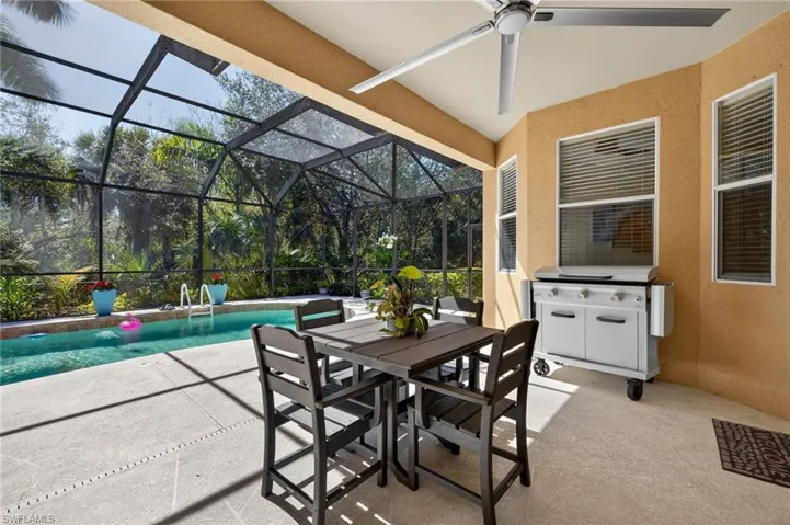 View of patio featuring a sunroom, outdoor dining space, a lanai, an outdoor pool, and a ceiling fan