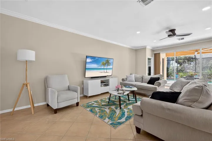 Living room with a ceiling fan, ornamental molding, light tile patterned floors, and recessed lighting