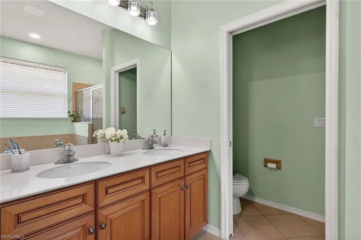Primary bathroom featuring double vanity, light tile patterned floors, and a shower stall