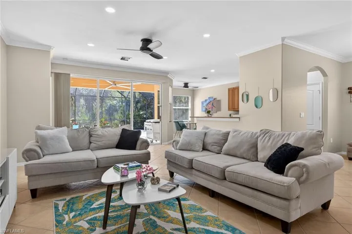Living area featuring ornamental molding, arched walkways, recessed lighting, ceiling fan, and a sunroom