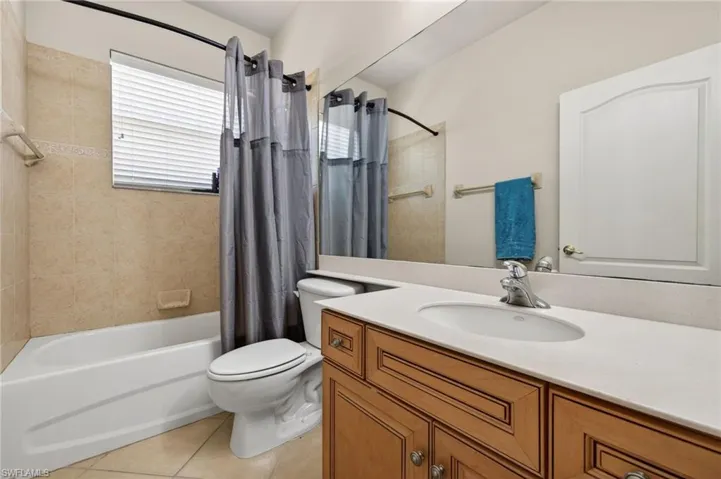 Full guest bath with vanity, shower / tub combo, and light tile patterned floors