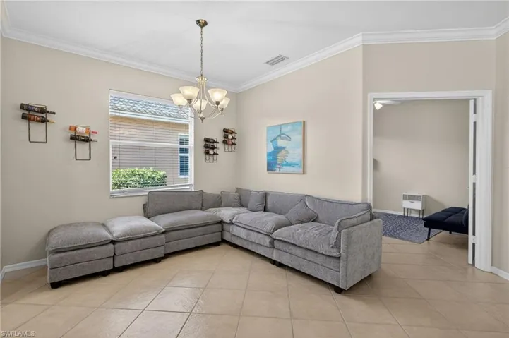 Living area featuring crown molding, light tile patterned floors, and hanging lights