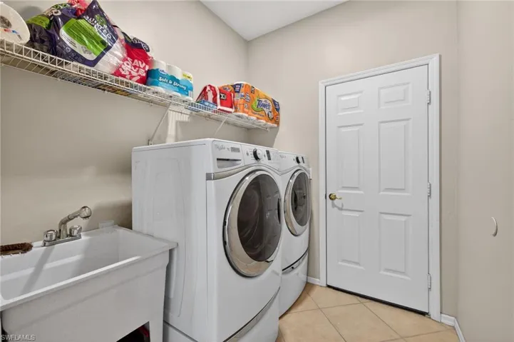 Laundry area featuring washing machine and dryer and light tile patterned floors