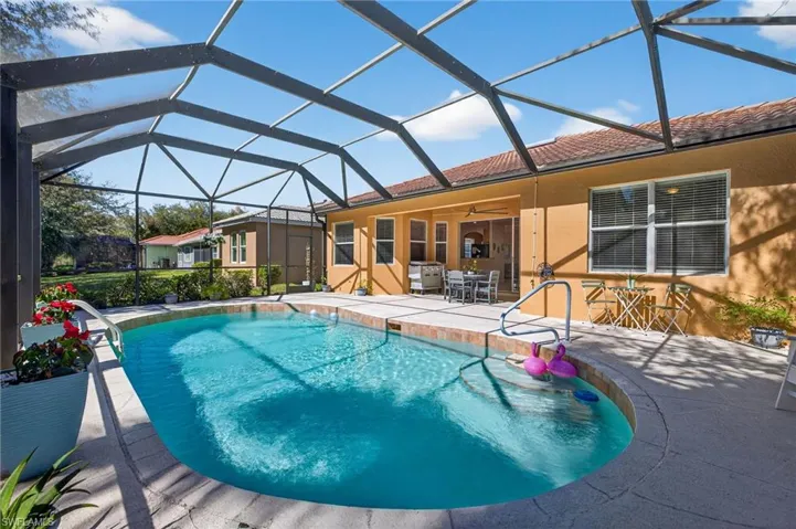 Swimming pool with a sunroom, glass enclosure, a patio area, and outdoor dining area