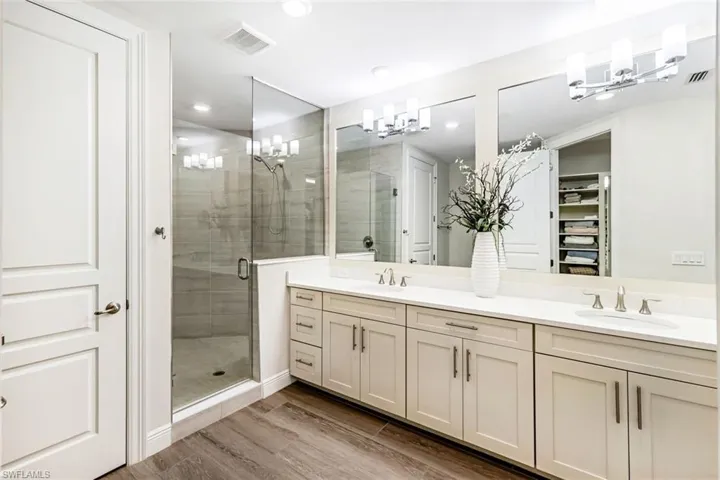 Primary bath with dual-sink vanity, step-in shower, water closet, and walk-in closet