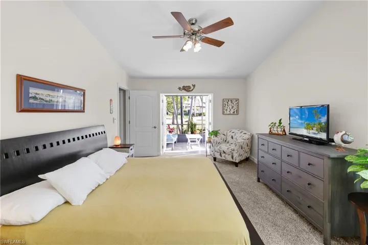 Carpeted bedroom featuring ceiling fan, access to outside, and vaulted ceiling