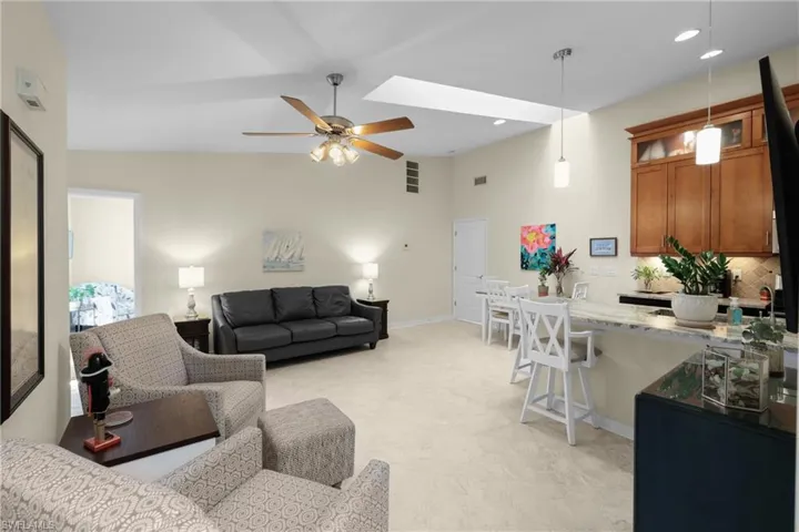Living room with ceiling fan and lofted ceiling with skylight
