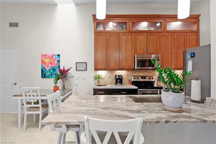 Kitchen with light stone counters, a kitchen bar, backsplash, and appliances with stainless steel finishes