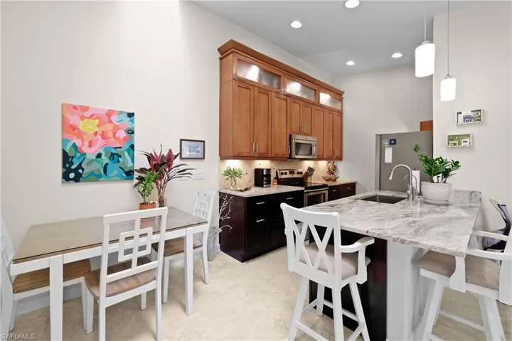 Kitchen with pendant lighting, sink, tasteful backsplash, light stone counters, and stainless steel appliances