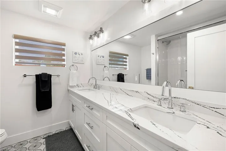 Full bathroom featuring double vanity and a stall shower