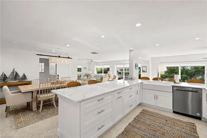 Kitchen featuring light stone countertops, stainless steel dishwasher, white cabinets, recessed lighting, and open floor plan
