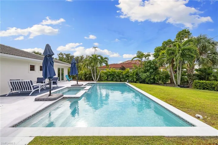 View of swimming pool featuring a patio area, a lawn, and a pool with connected hot tub