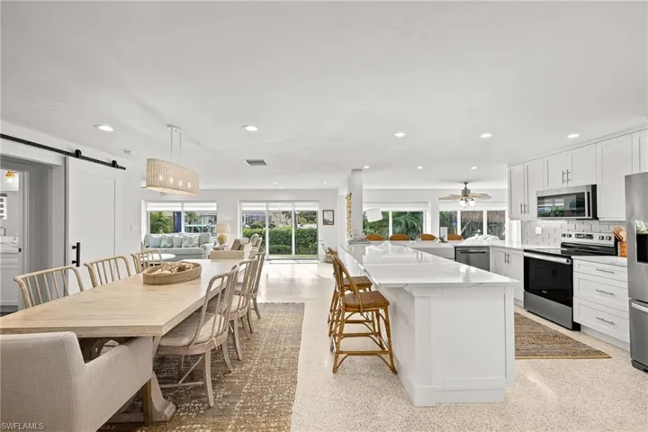Kitchen with a barn door, open floor plan, appliances with stainless steel finishes, white cabinets, and a kitchen breakfast bar