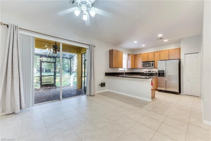 Kitchen featuring appliances with stainless steel finishes, a ceiling fan, dark countertops, recessed lighting, and light tile patterned flooring