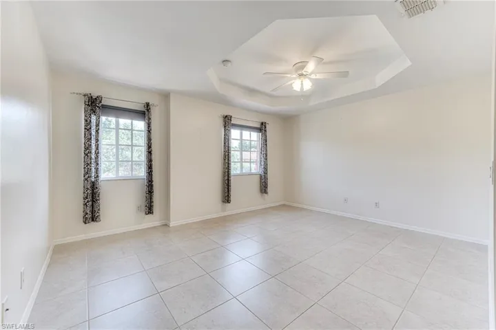 Master bedroom with plenty of natural light, ceiling fan, and a tray ceiling