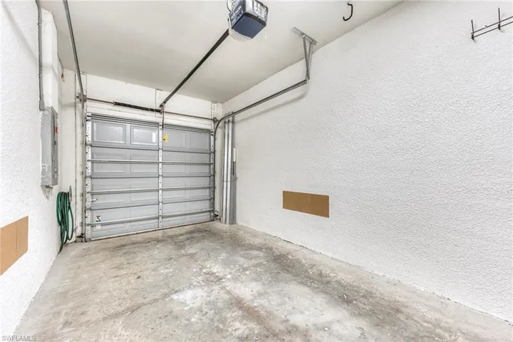 Garage with a garage door opener, a textured wall, and electric panel