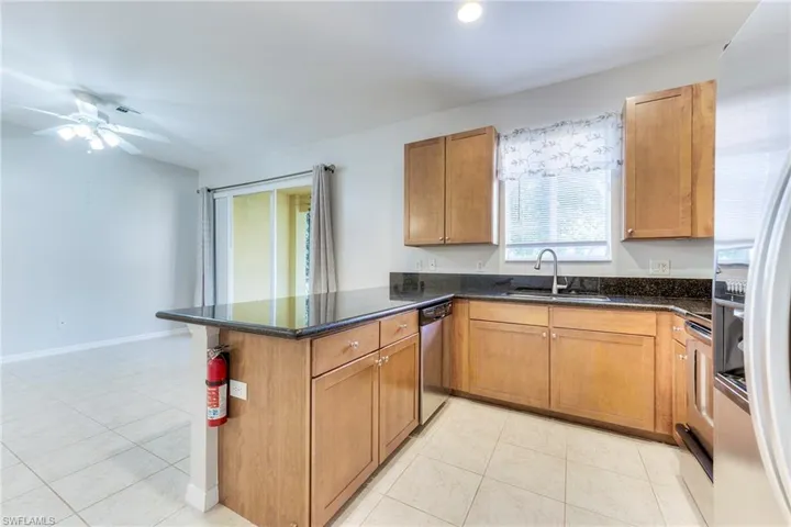 Kitchen featuring fridge with ice dispenser, a peninsula, dishwasher, and light tile patterned floors