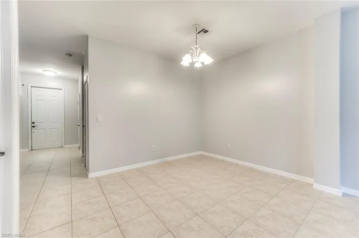 Unfurnished room with a chandelier and light tile patterned flooring