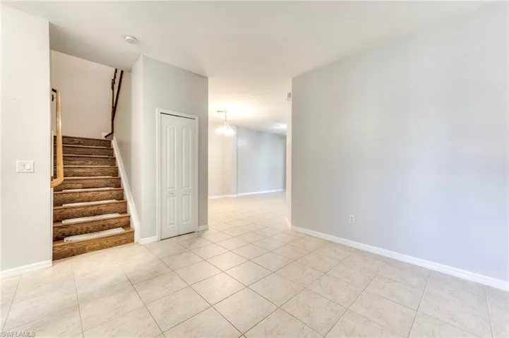 Empty room with light tile patterned floors, stairs, and a smoke detector