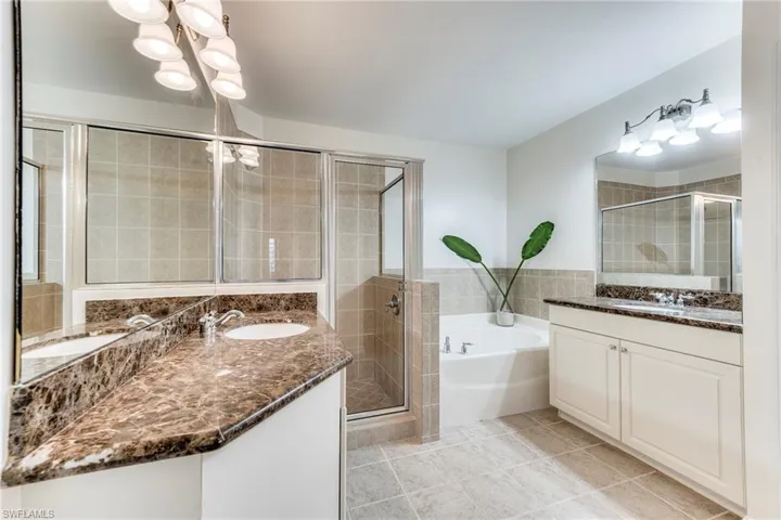 Master bathroom with two vanities, a bath, a shower stall, and tile patterned flooring