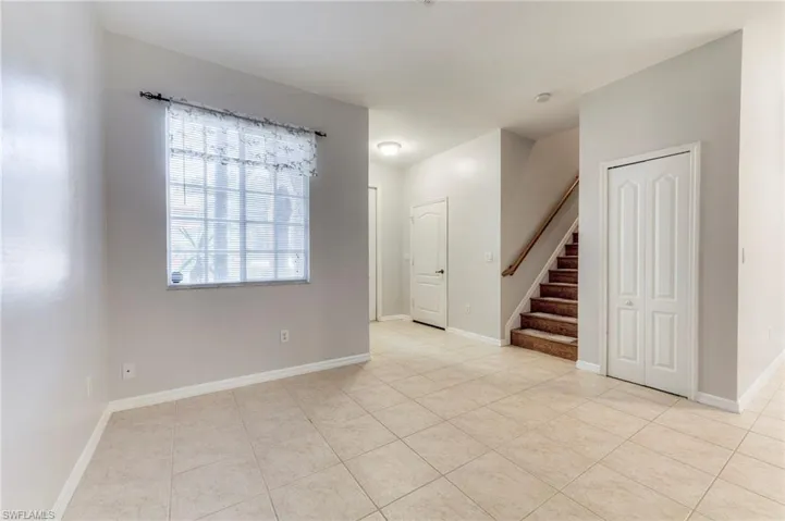Empty room featuring stairway and light tile patterned floors