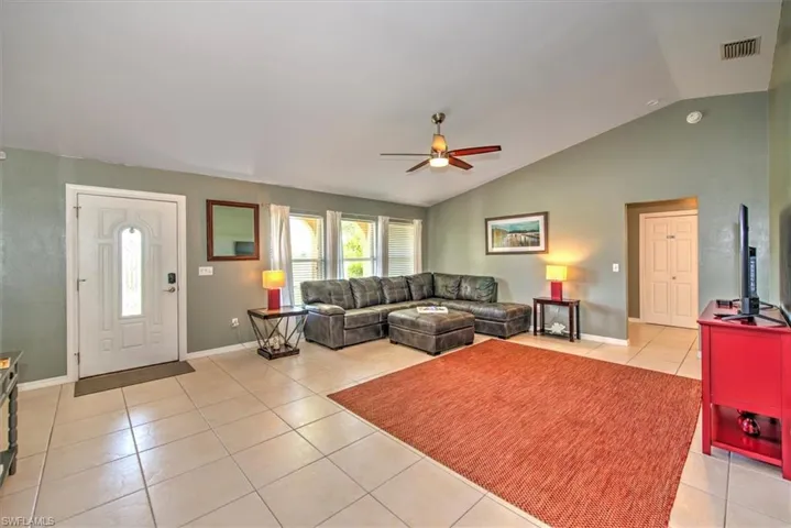 Tiled living room with ceiling fan and lofted ceiling