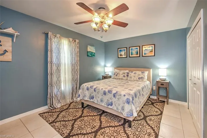 Tiled bedroom with ceiling fan and a closet