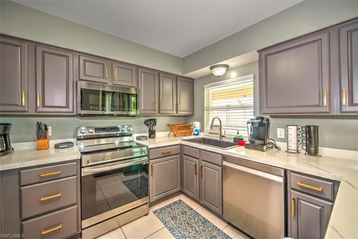 Kitchen featuring stainless steel appliances, sink, and light tile floors