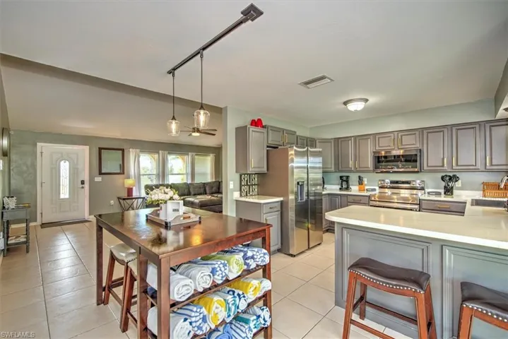 Kitchen with stainless steel appliances, pendant lighting, sink, track lighting, and light tile floors