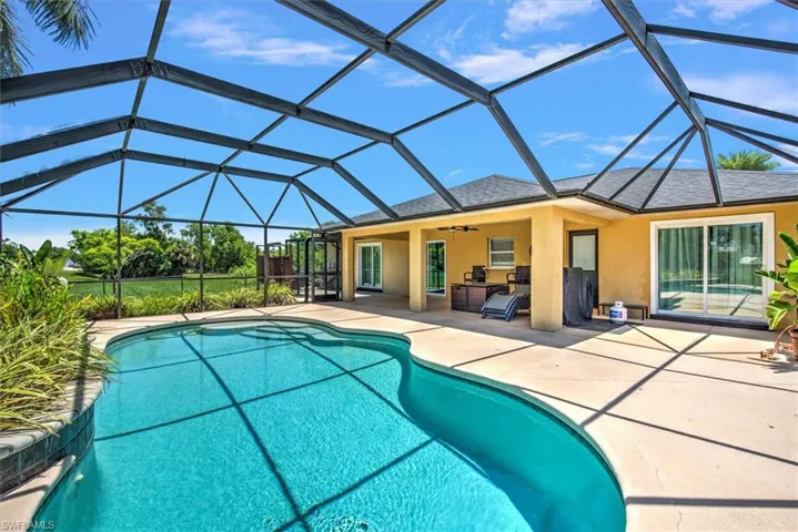 View of pool featuring a patio area, glass enclosure, and ceiling fan