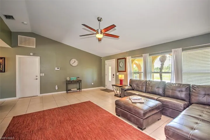 Tiled living room with lofted ceiling and ceiling fan