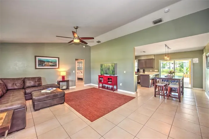 Tiled living room featuring ceiling fan and lofted ceiling
