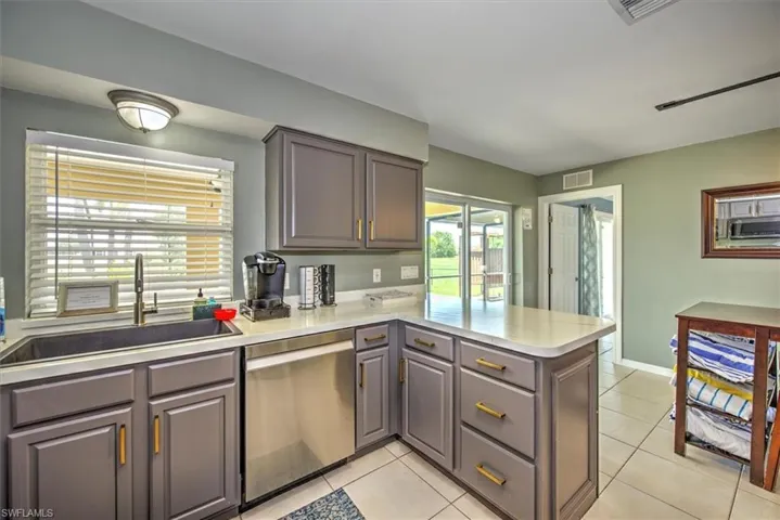 Kitchen with kitchen peninsula, light tile floors, and appliances with stainless steel finishes