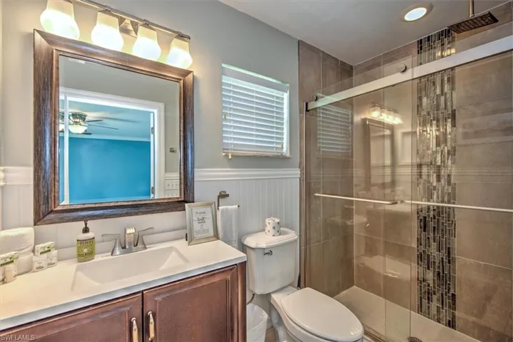 Bathroom featuring walk in shower, vanity, toilet, and ceiling fan