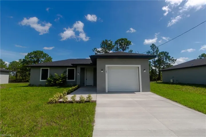 Ranch-style home with stucco siding, concrete driveway, an attached garage, and a front lawn